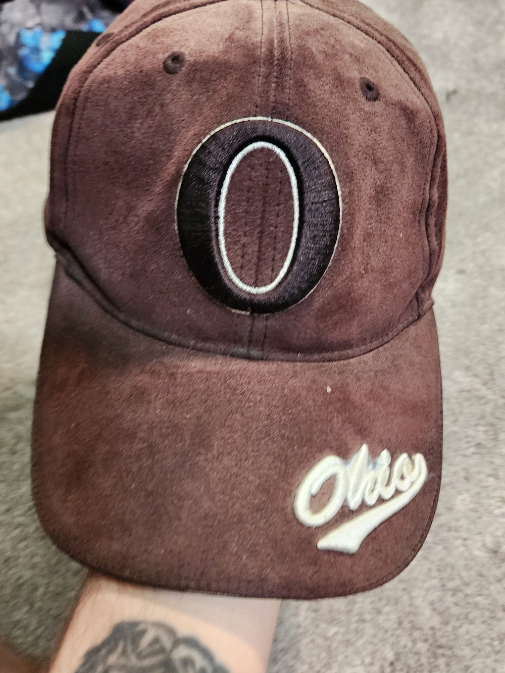 brown suede baseball hat featuring a circular O patch on the front